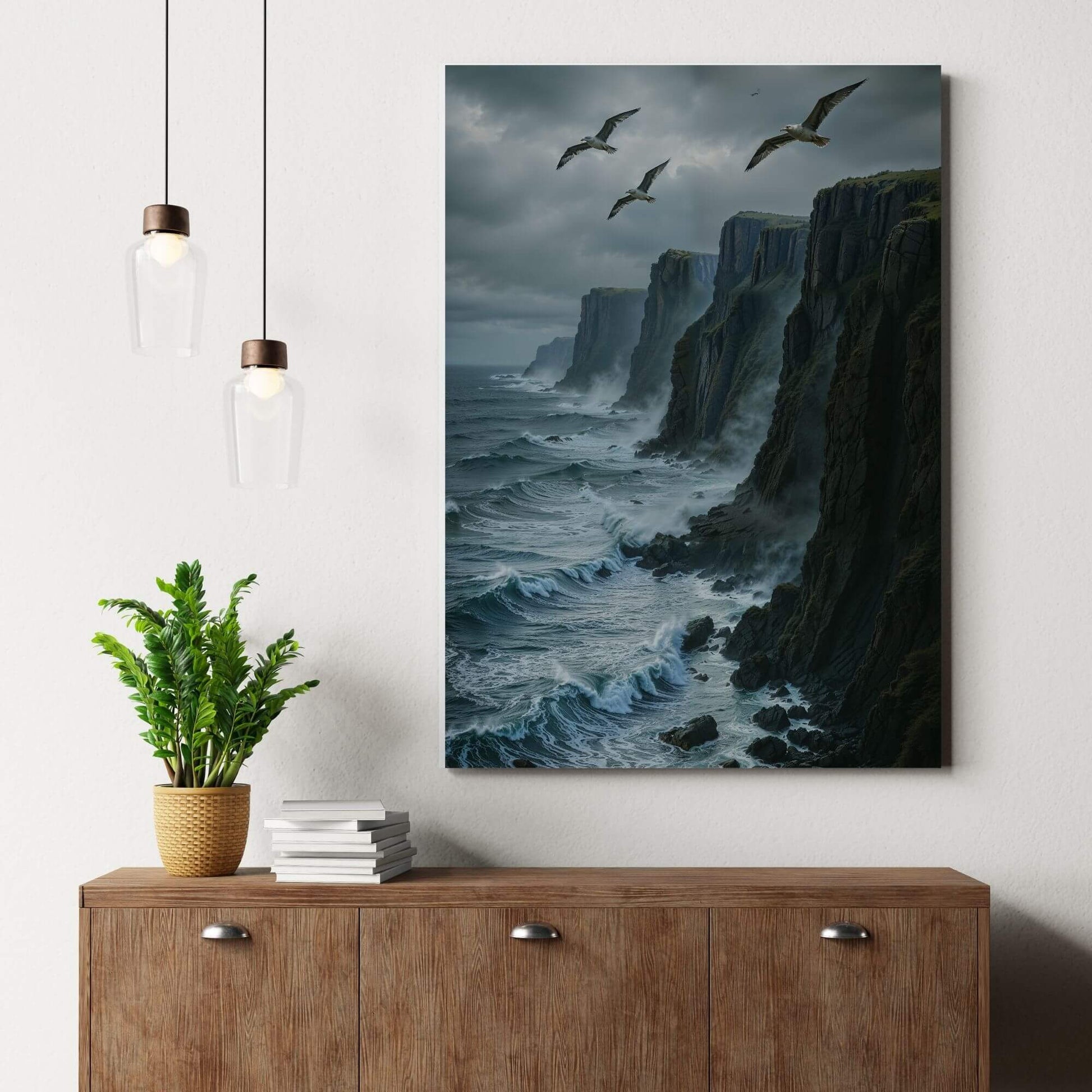 Canvas print of a dramatic coastal landscape with cliffs and seagulls, placed on a wooden dresser with a plant, suitable for coastal or seascape decor.