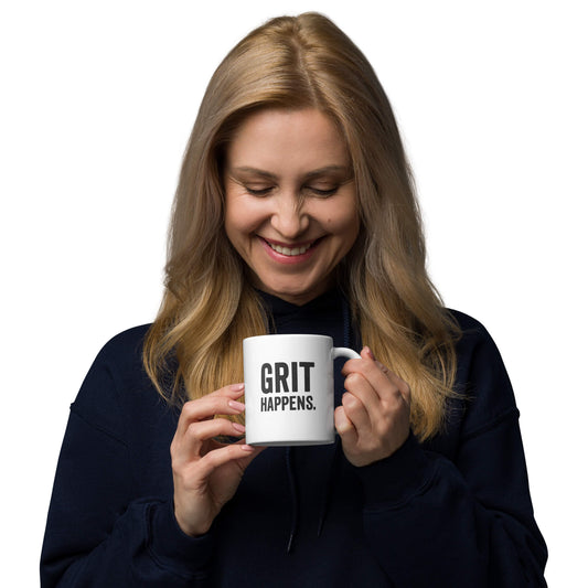 Woman smiling while holding the 11oz "Grit Happens" white ceramic coffee mug by Grit Collective.