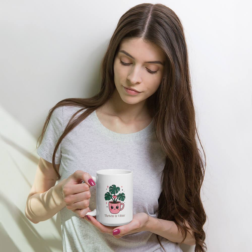 Woman looking at a Grit Collective Kawaii Thriving Plant Pal design printed on a 15oz white glossy ceramic coffee mug.
