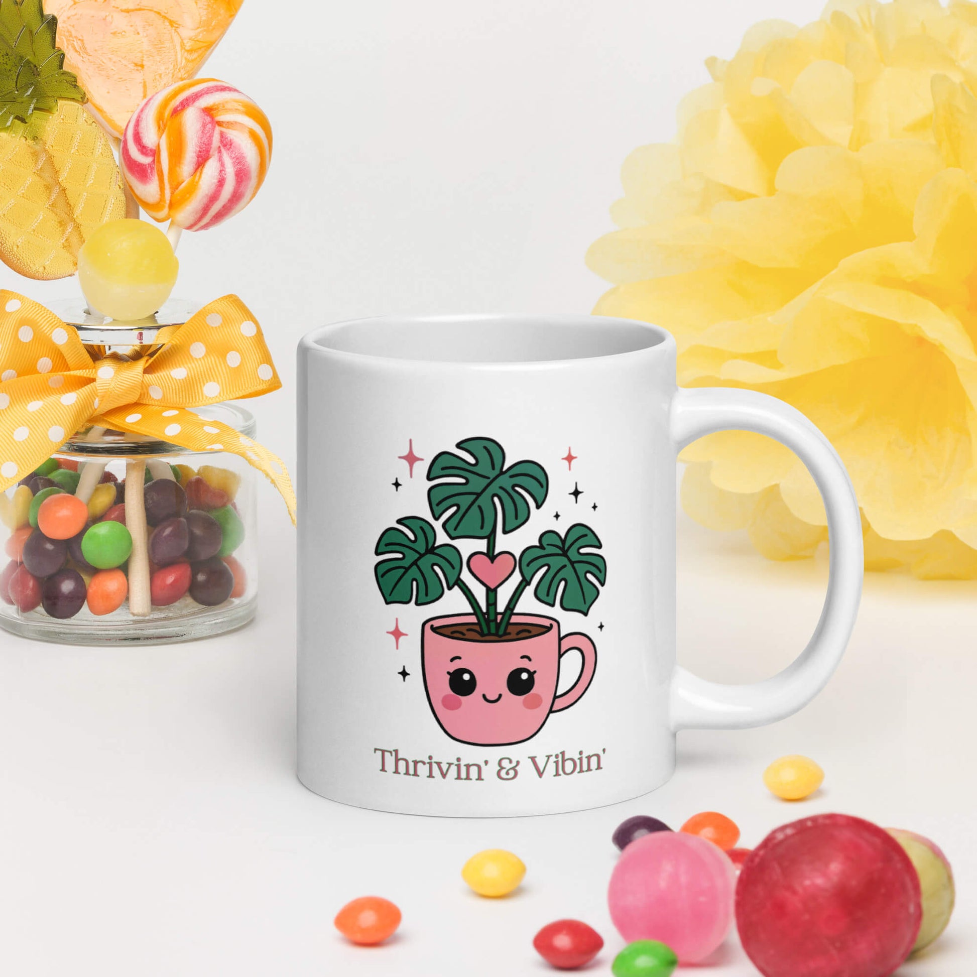 Grit Collective Kawaii Thriving Plant Pal design printed on a 20oz white glossy ceramic coffee mug, shown in a colorful scene with candy.