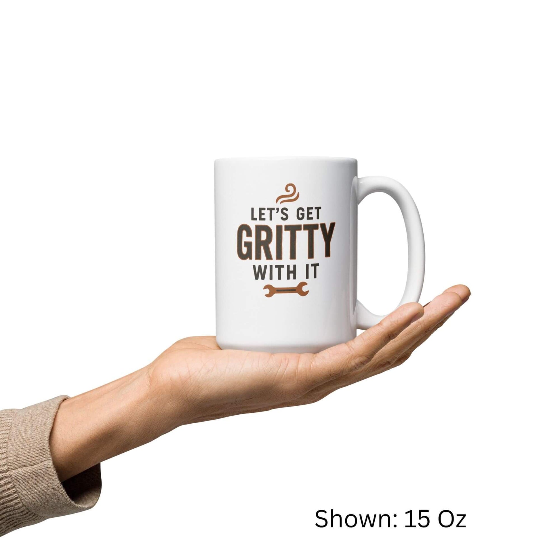 Grit Collective "Let's Get Gritty With It" wrench design printed on a 15oz white glossy ceramic coffee mug, held in a hand.