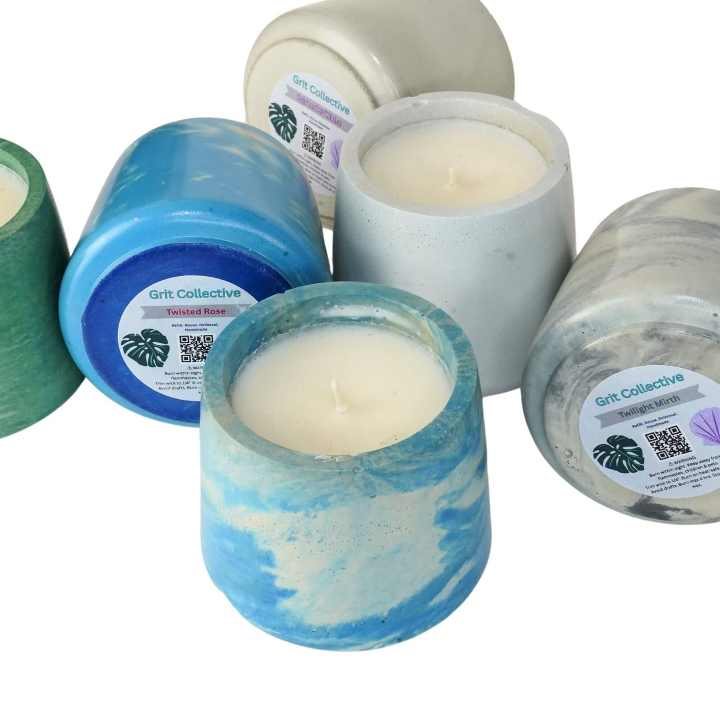 Close-up of Grit Collective Sea Stone Concrete Candles, including blue marble and green, with scent labels like 'Twisted Rose' visible on the 6oz soy wax candles.