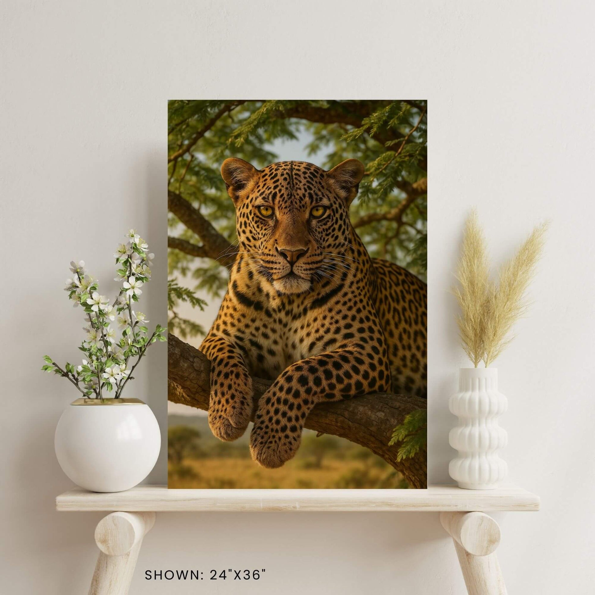 24 × 36-inch African leopard lounging on an acacia branch canvas wall art styled on a minimalist shelf with vase florals and pampas grass.