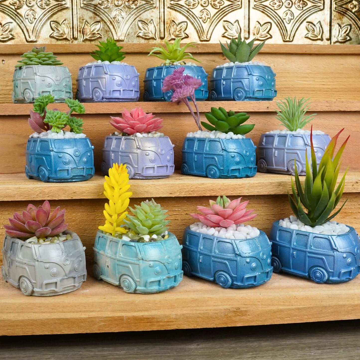 Large display of numerous handmade mini retro bus concrete planters in a variety of colors and with different artificial succulents, arranged on wooden steps.