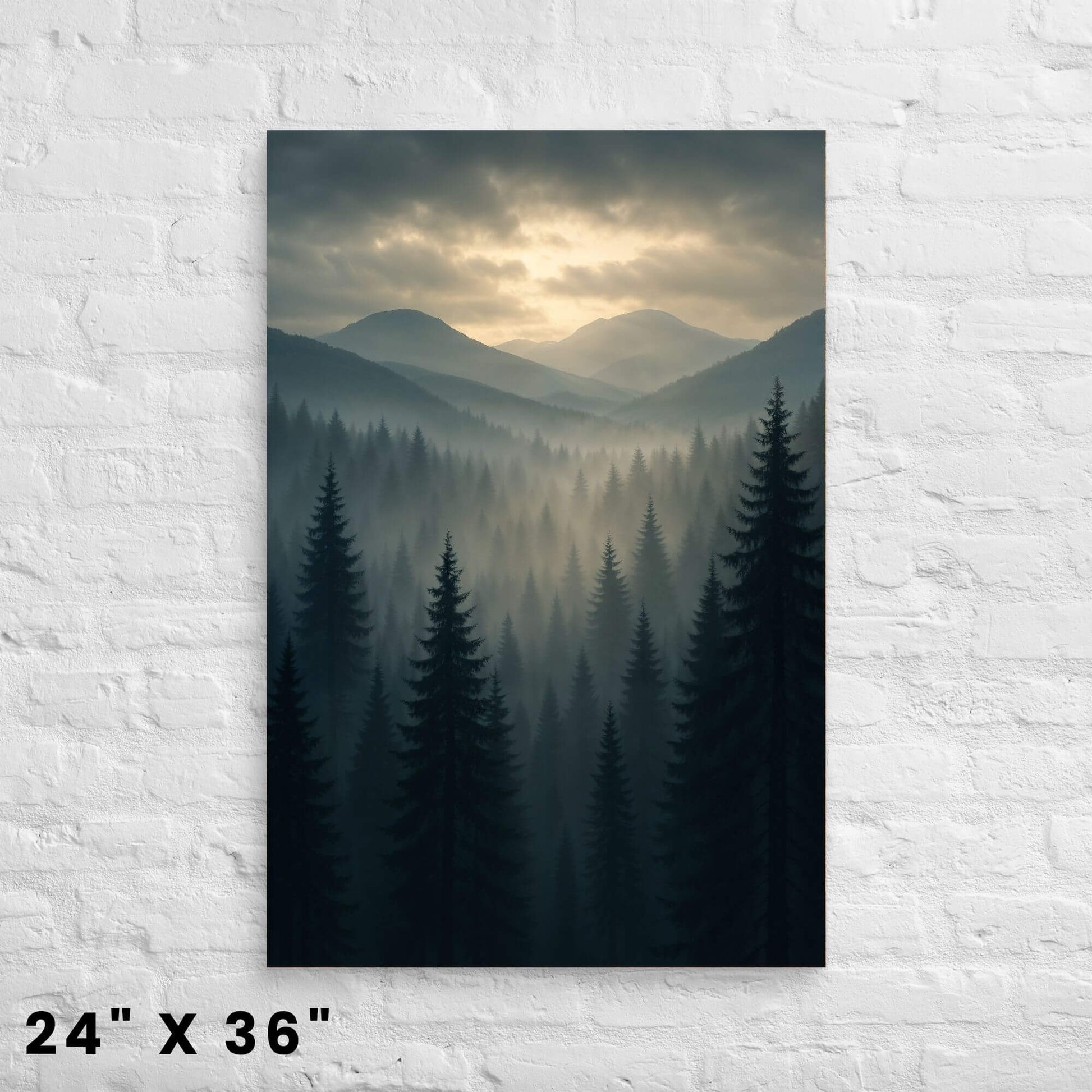 24 × 36-inch moody mist-filled mountain-forest canvas print with dawn light breaking through clouds, displayed on a bright white-brick wall.
