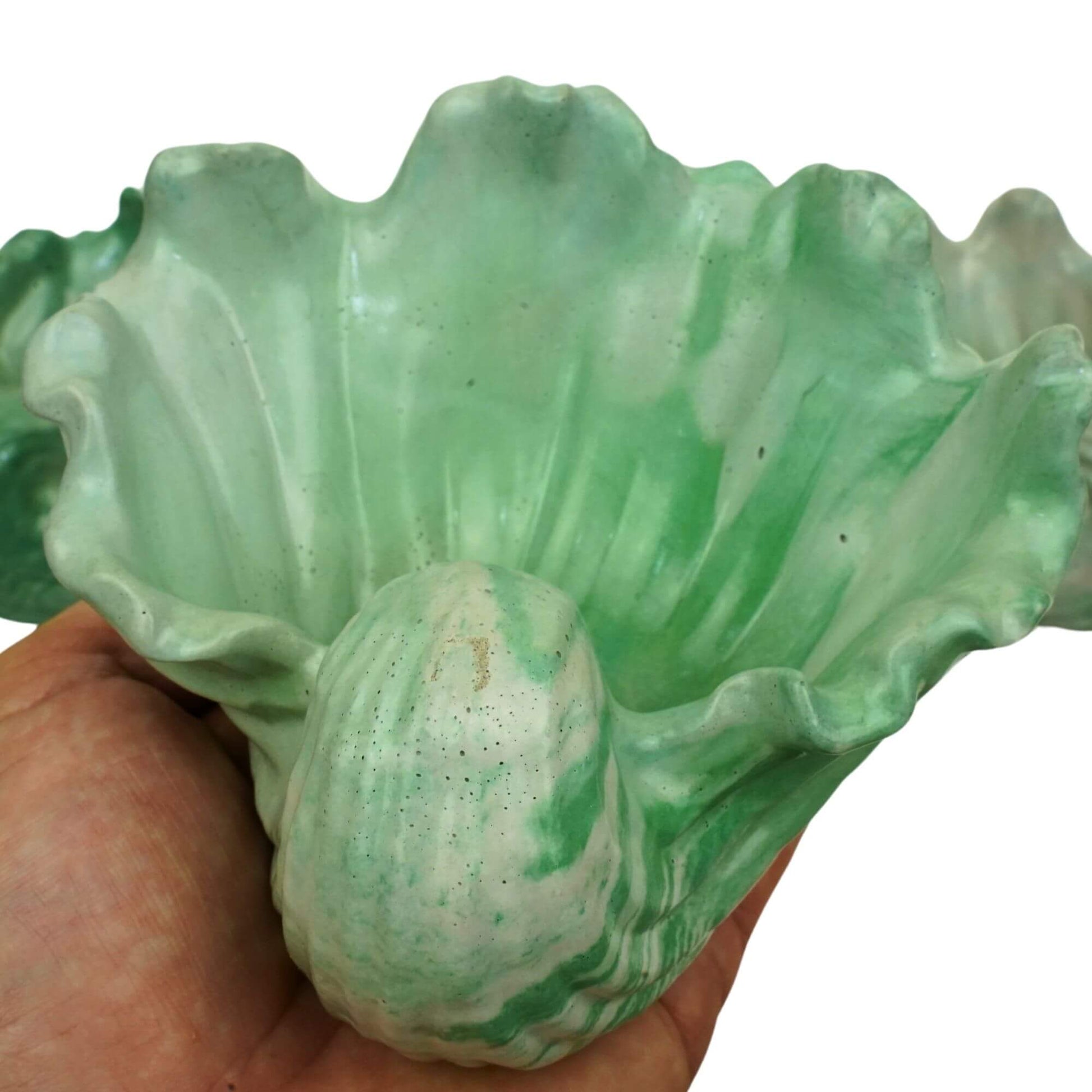 Hand holding a single green and concrete colored Ocean Bowl, a handcrafted coastal concrete dish.