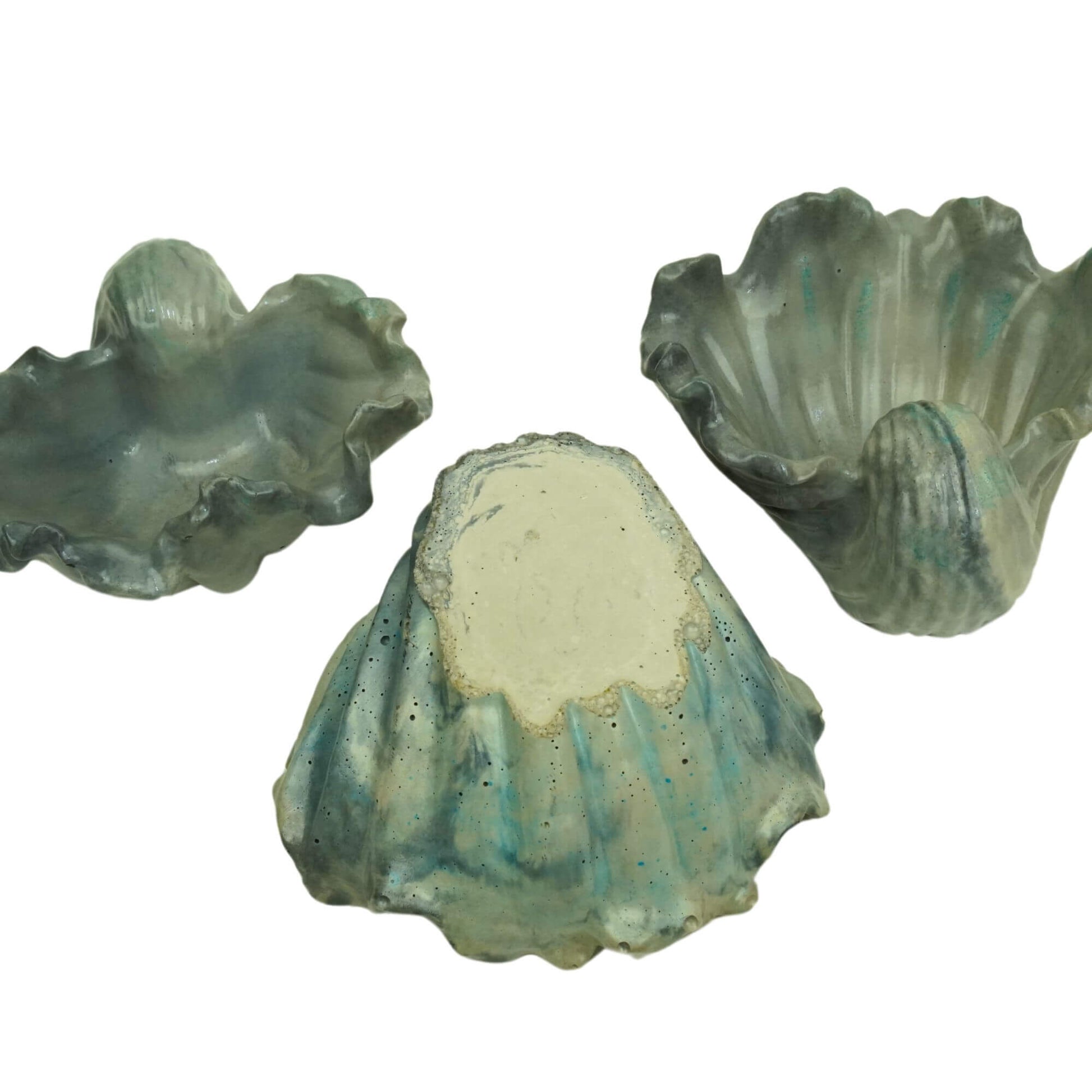 Bottom view of a set of three handcrafted concrete Ocean Bowls in green, gray and blue, showing the concrete texture.