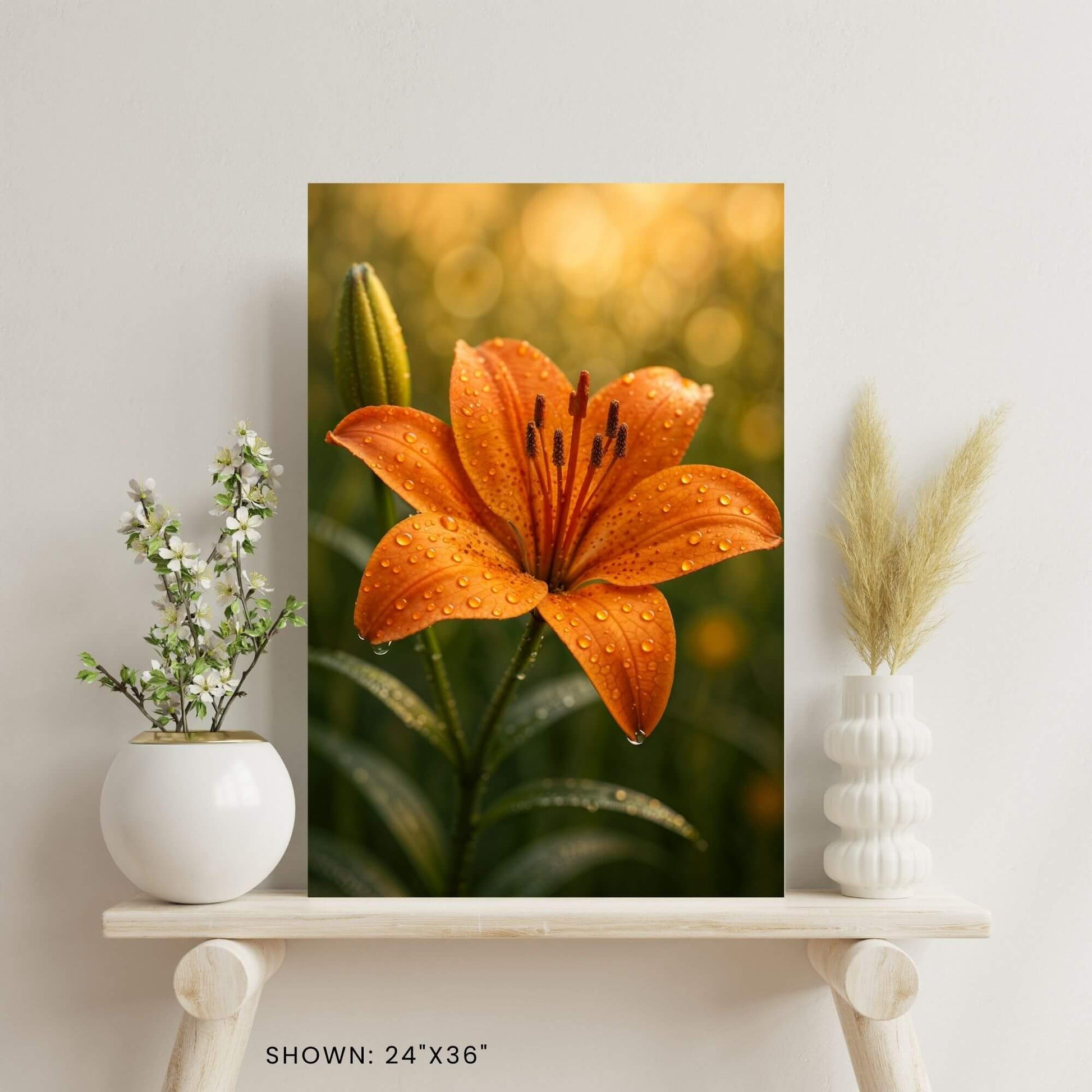 24"x36" canvas print featuring a close-up of an orange lily covered in water droplets, presented on
a wooden shelf.