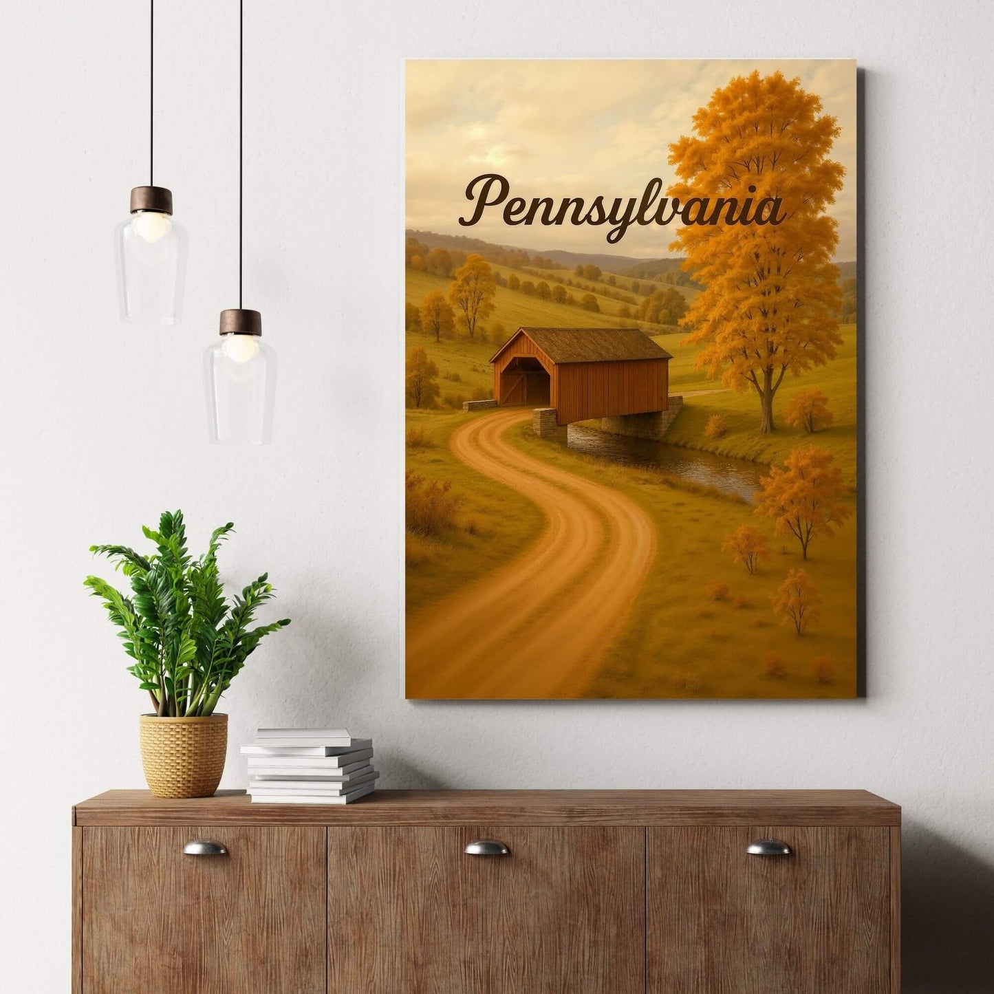 Canvas print of a Pennsylvania covered bridge scene in autumn, placed on a wooden dresser with
a potted plant and books.