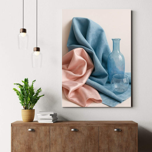 Canvas print of a still life with blue and pink fabric and glass objects, placed on a wooden dresser with a plant, suitable for still life art decor.