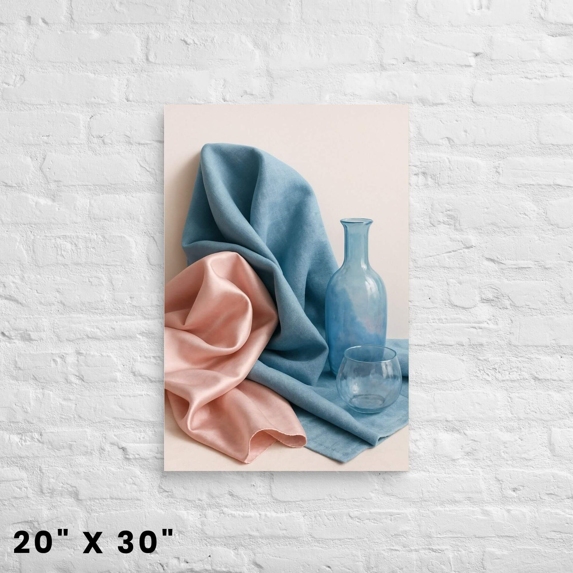 20"x30" canvas print of a still life composition with blue and pink fabric, a blue bottle, and a glass, hanging on a white brick wall.