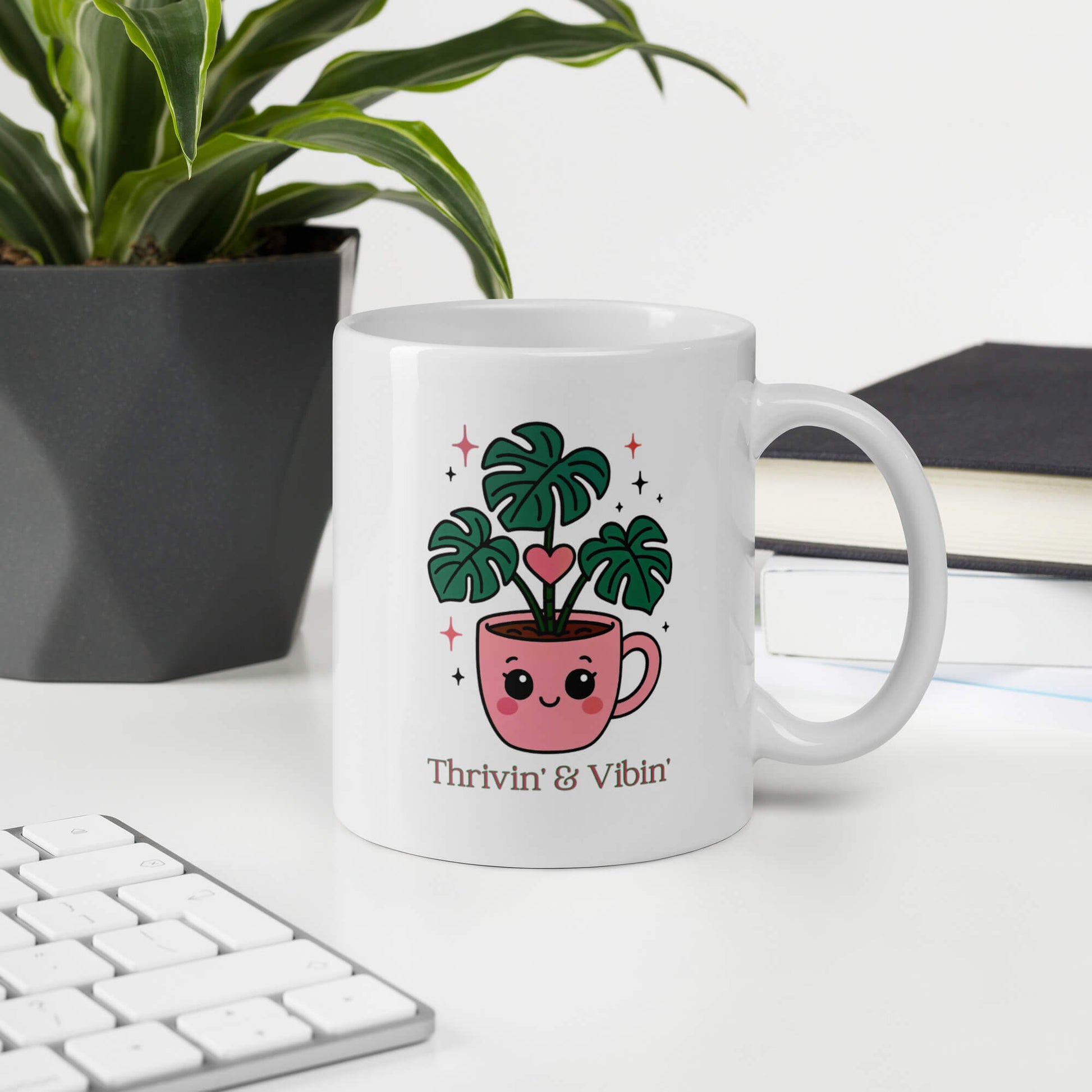 Grit Collective Kawaii Thriving Plant Pal design printed on an 11oz white glossy ceramic coffee mug, shown in an office environment.